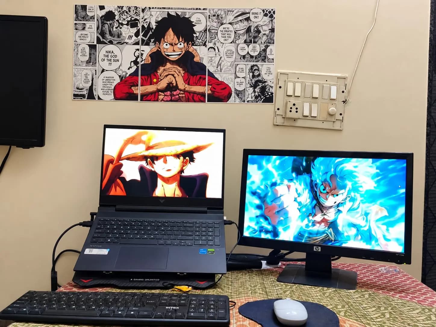Black-and-white Luffy manga triptych on the wall above a laptop and monitor desk